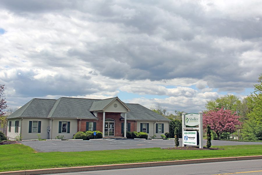 About Our Agency - Landscape View of Trees and Sky Along With Sholley Agency Main Office Building